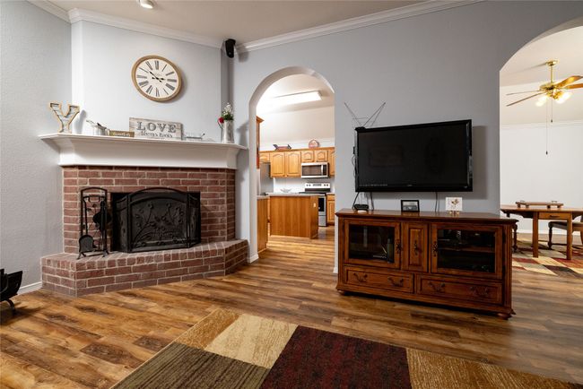Living area with arched walkways, wood finished floors, crown molding, and ceiling fan | Image 10