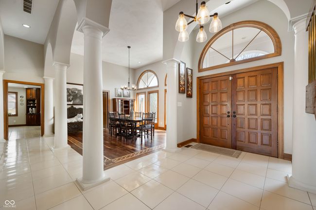 tiled entrance foyer with visible vents, a towering ceiling, decorative columns, baseboards, and a chandelier | Image 5