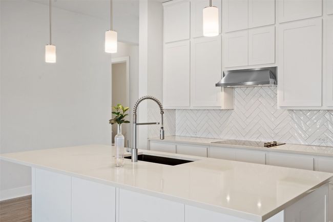 Kitchen featuring decorative backsplash, white cabinets, and wall chimney exhaust hood | Image 12