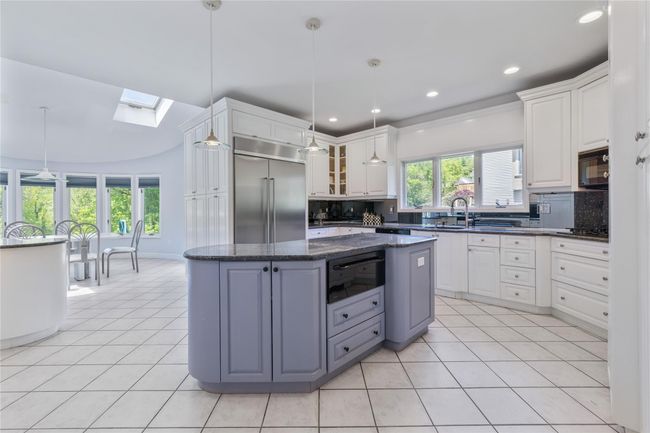 Kitchen featuring stainless steel built in refrigerator, black microwave, a warming drawer, a skylight, and tasteful backsplash | Image 13