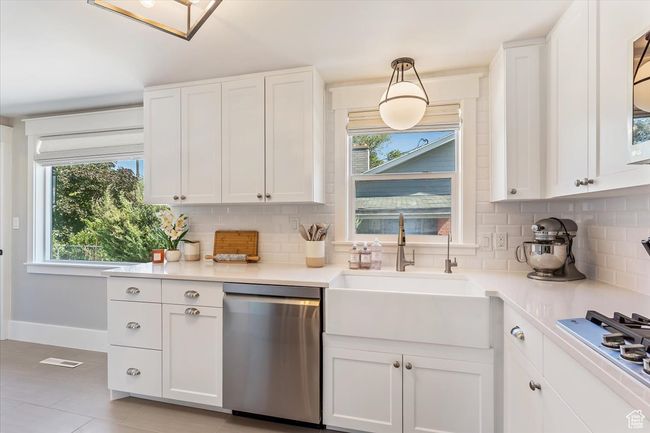 Kitchen featuring stainless steel appliances, decorative backsplash, healthy amount of natural light, and white cabinets | Image 15