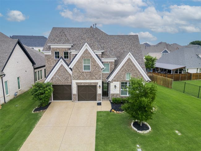 View of front of home featuring roof with shingles, driveway, a garage, stone siding, and brick siding | Image 34