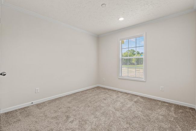 Empty room with a textured ceiling, baseboards, ornamental molding, and carpet floors | Image 27