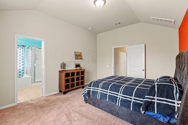 Carpeted bedroom featuring lofted ceiling, tile patterned floors, visible vents, and connected bathroom | Image 7