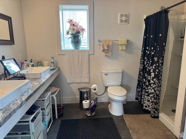 Full bath with concrete flooring, a stall shower, baseboards, toilet, and a sink | Image 19