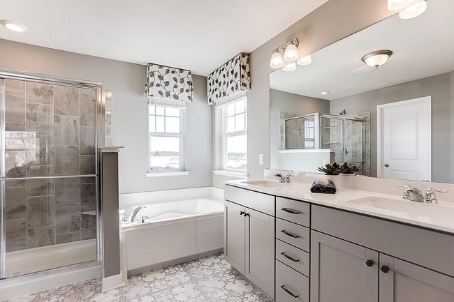 An extension of the primary suite, this private & spacious bathroom contains a double-vanity, a separate shower and tub, a private water closet, plus TWO walk-in closets. Photo of model home, color & options may vary. | Image 13