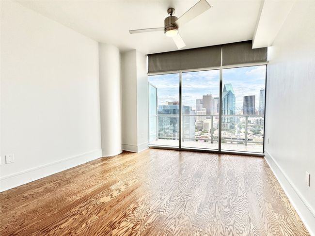 Spare room with a skyline view, wood finished floors, ceiling fan, baseboards, and a wall of windows | Image 16