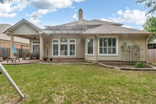 Rear view of property featuring a chimney, fence, a patio area, a lawn, and ceiling fan | Image 34