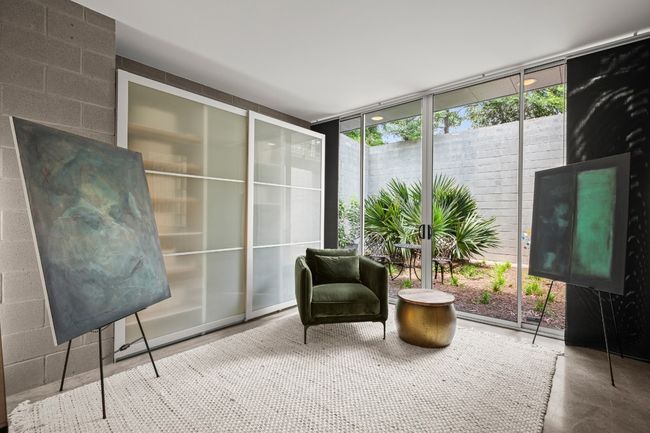 4th bedroom OR guest apartment downstairs. This room has a private entrance from the carport as well as double sliding doors to its own private garden space. Currently staged as an art display. See virtual staging photos to show this room as a bedroom and office. | Image 30