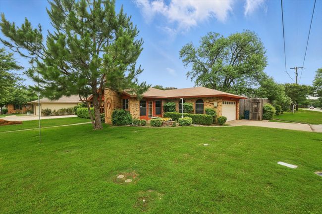 Ranch-style house featuring concrete driveway, a garage, and a front lawn | Image 7