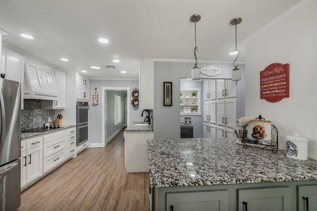 Kitchen with appliances with stainless steel finishes, crown molding, backsplash, light wood-style floors, and white cabinetry | Image 9