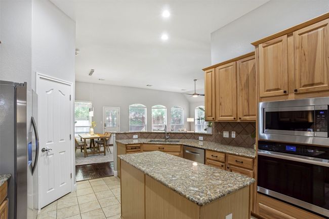 Kitchen featuring appliances with stainless steel finishes, a sink, tasteful backsplash, and light stone counters | Image 6