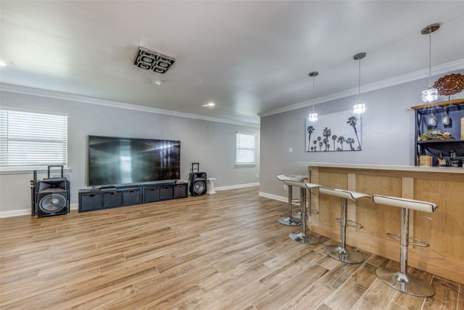 Indoor dry bar featuring wood finished floors, crown molding, and hanging light fixtures | Image 10