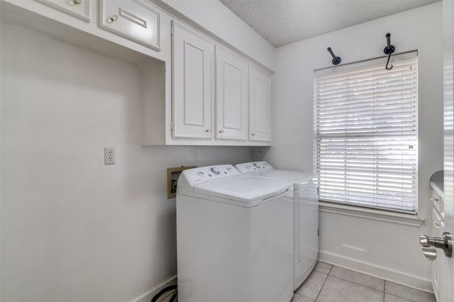 Laundry room featuring cabinet space, washing machine and dryer, baseboards, and light tile patterned flooring | Image 19