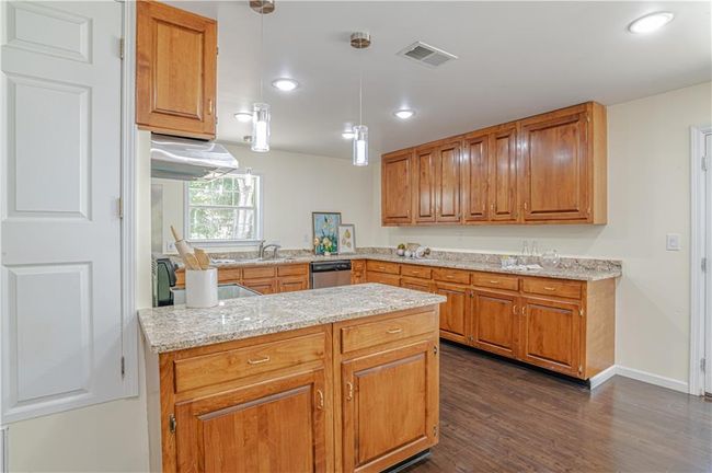 Kitchen featuring dishwasher, light stone counters, dark hardwood / wood-style flooring, kitchen peninsula, and pendant lighting | Image 24
