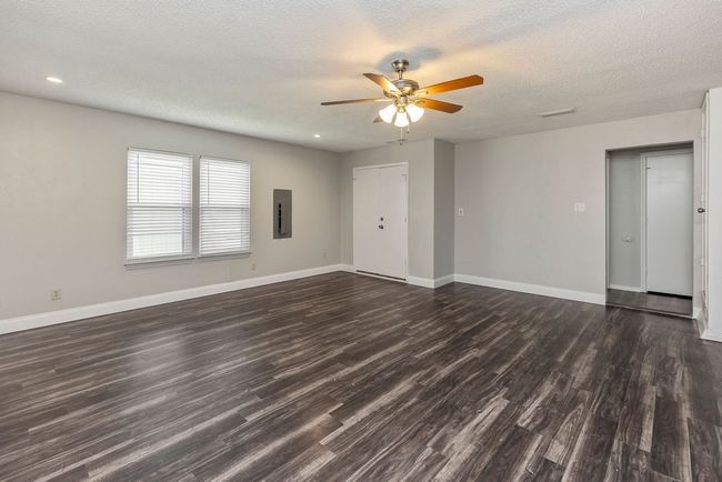 Unfurnished living room with dark wood finished floors, ceiling fan, baseboards, a textured ceiling, and electric panel | Image 12
