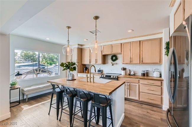 Kitchen with appliances with stainless steel finishes, butcher block countertops, light brown cabinetry, a sink, and recessed lighting | Image 11