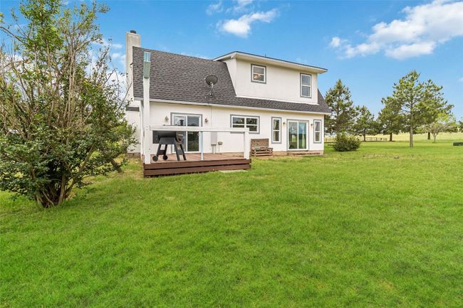 Rear view of house featuring stucco siding, a chimney, a deck, a shingled roof, and a yard | Image 29