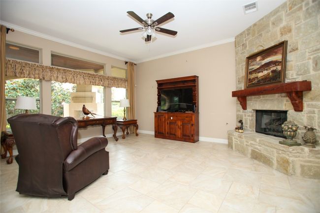 Living area with a ceiling fan, ornamental molding, a fireplace, and baseboards | Image 4