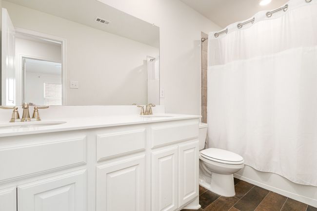Bathroom featuring a sink, visible vents, toilet, and shower / tub combo with curtain | Image 25