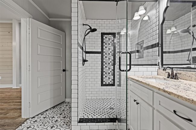 Bathroom featuring baseboards, wood walls, a shower stall, vanity, and ornamental molding | Image 23