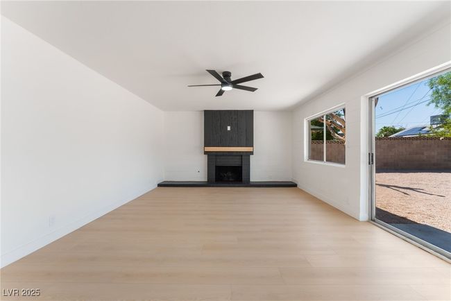 Unfurnished living room with light wood-type flooring, plenty of natural light, a ceiling fan, and a large fireplace | Image 11