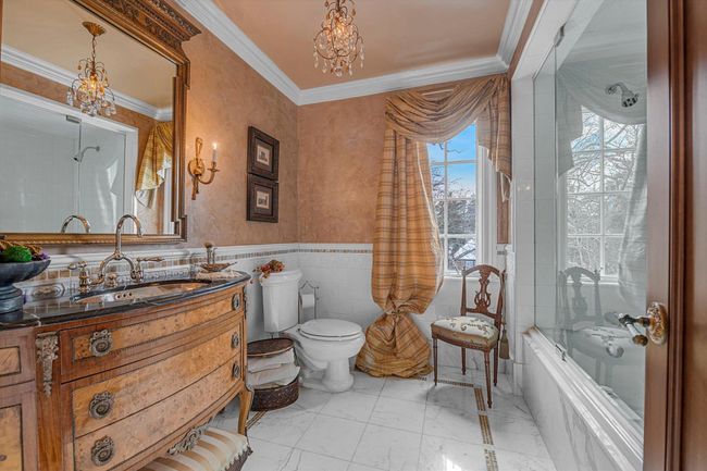 Full bathroom with a notable chandelier, ornamental molding, toilet, and tiled shower / bath | Image 19