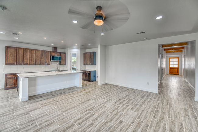 Kitchen with a breakfast bar, ceiling fan, sink, and an island with sink | Image 36