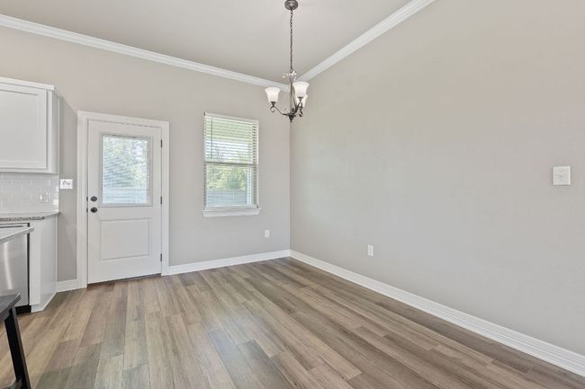 Unfurnished dining area featuring light wood-style floors, crown molding, and a chandelier | Image 8