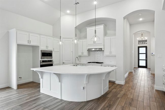 Kitchen with white cabinets, light countertops, tile floors, and high vaulted ceiling | Image 7
