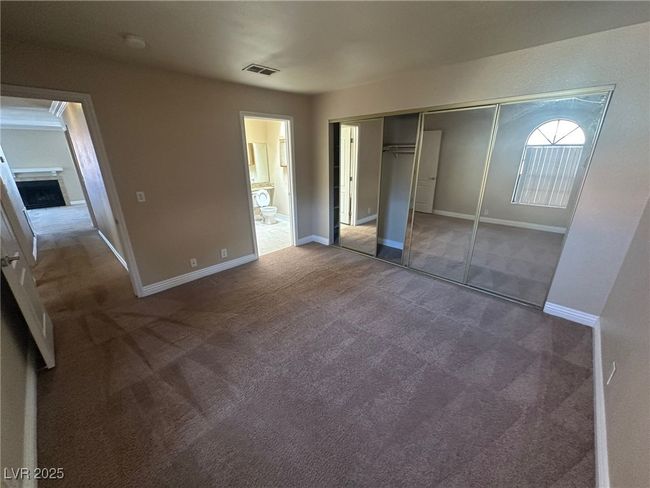 Unfurnished bedroom with connected bathroom, visible vents, carpet floors, and baseboards | Image 18