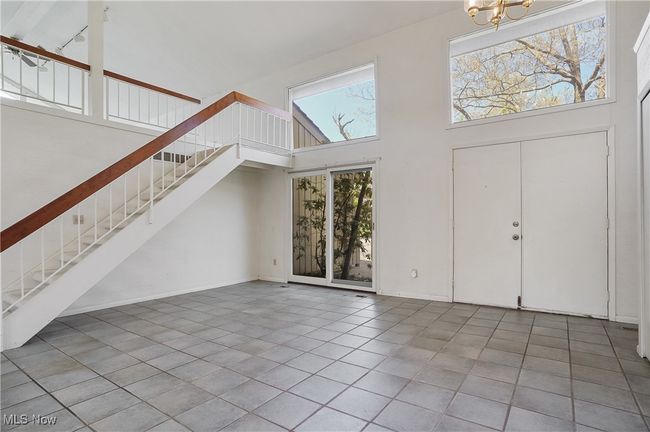 Foyer entrance featuring stairway, tile patterned floors, a chandelier, a towering ceiling, and baseboards | Image 5