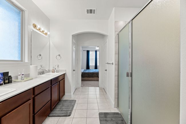 Ensuite bathroom featuring a sink, tile patterned floors, a stall shower, visible vents, and ensuite bathroom | Image 23