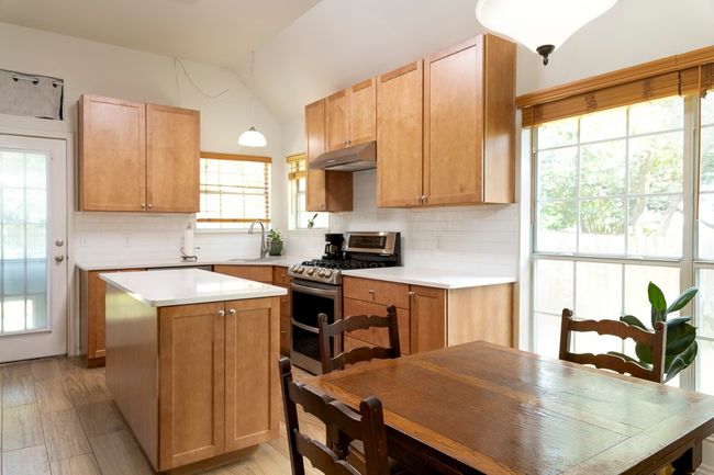 Kitchen featuring double oven range, under cabinet range hood, vaulted ceiling, backsplash, and light countertops | Image 9
