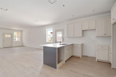 Kitchen with white cabinets, kitchen peninsula, light wood-type flooring, and sink | Image 3