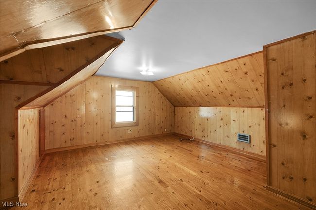 primary bedroom with wood / wood-style floors, visible vents, wooden walls, and vaulted ceiling | Image 18