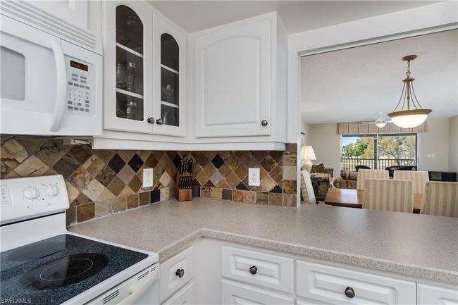 Kitchen featuring decorative backsplash, white appliances, and glass insert cabinets | Image 17