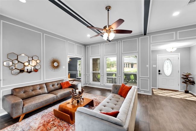 Living room featuring a decorative wall, a ceiling fan, wood finished floors, ornamental molding, and recessed lighting | Image 10