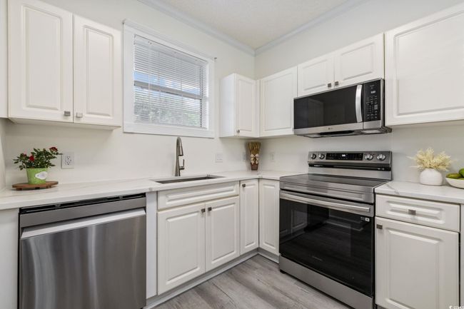 Kitchen featuring appliances with stainless steel finishes, crown molding, white cabinets, and light countertops | Image 10