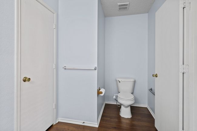 Bathroom with hardwood / wood-style flooring, a textured ceiling, and toilet | Image 13