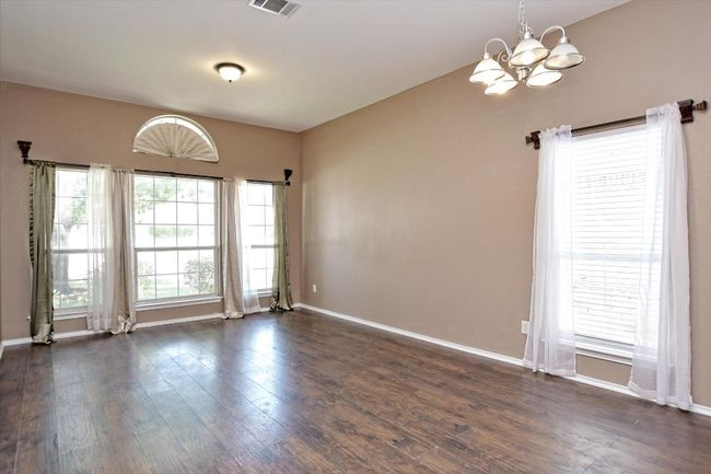 Unfurnished room featuring a chandelier, dark wood-style floors, and baseboards | Image 6