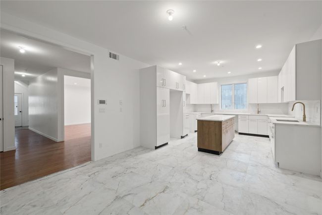 Kitchen featuring a center island, a sink, white cabinetry, recessed lighting, and baseboards | Image 8