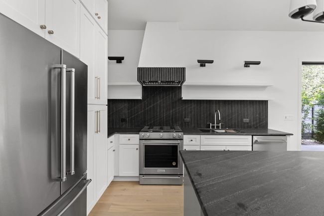Kitchen featuring stainless steel appliances, open shelves, tasteful backsplash, white cabinets, and light wood finished floors | Image 9