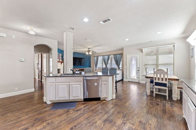 Kitchen featuring stainless steel appliances, tasteful backsplash, arched walkways, dark wood-type flooring, and a sink | Image 5