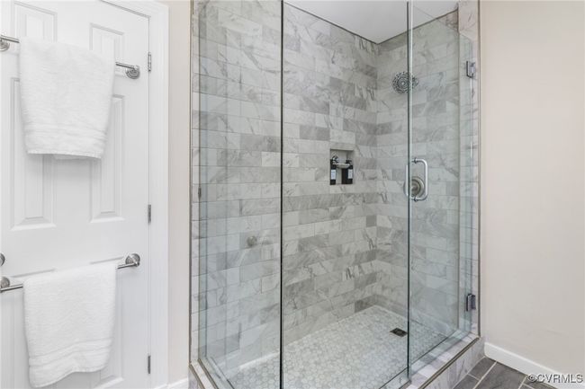 Primary bathroom with a large tiled shower, dual vanity, tiled flooring and linen closet. | Image 25