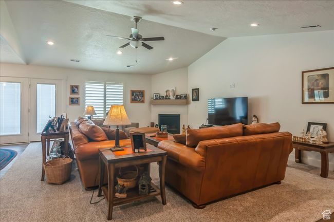 Carpeted living room with vaulted ceiling, recessed lighting, ceiling fan, and a glass covered fireplace | Image 7