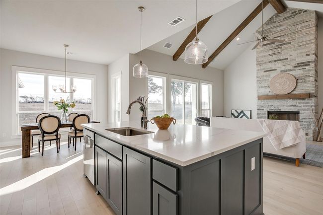 Kitchen featuring a fireplace, beam ceiling, sink, an island with sink, and gray cabinetry | Image 17