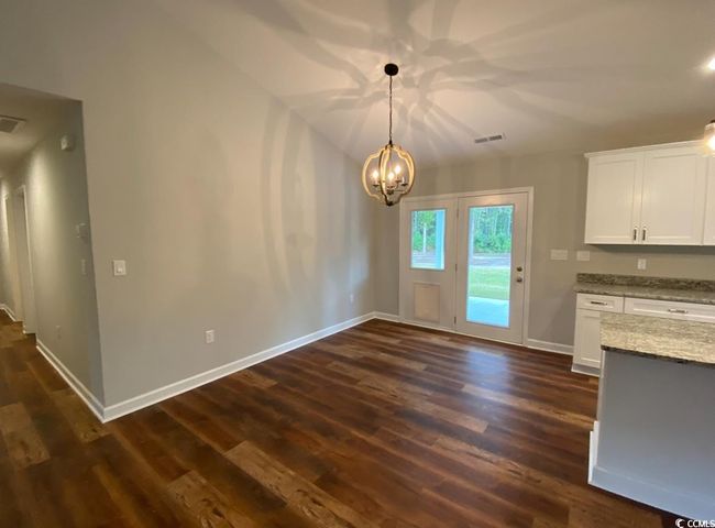 Unfurnished dining area with dark wood-type flooring, a chandelier, and baseboards | Image 13