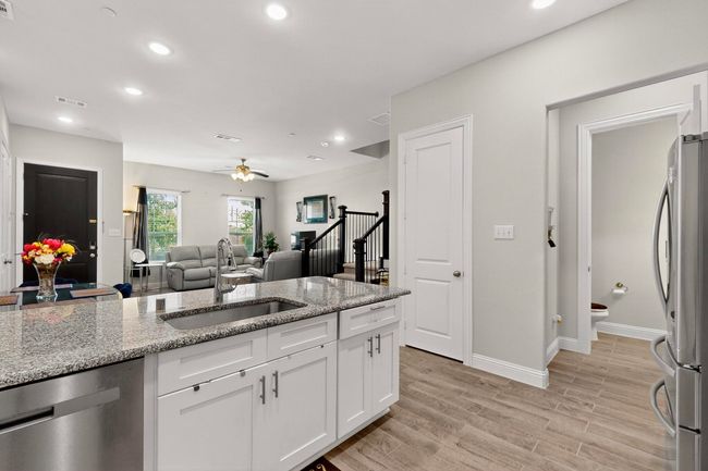 Kitchen featuring stainless steel appliances, white cabinetry, light stone countertops, recessed lighting, and light wood-style flooring | Image 11