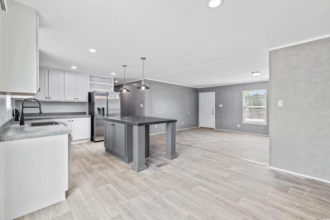 Kitchen featuring stainless steel fridge with ice dispenser, a breakfast bar area, light wood-style flooring, a kitchen island, and recessed lighting | Image 18